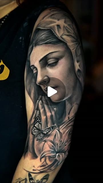 Detailed Virgin of Guadalupe tattoo with flowers and soft black-and-grey shading.